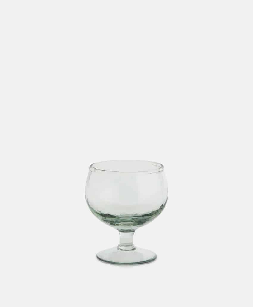 A clear, empty, stemmed glass goblet is centered on a plain white background.