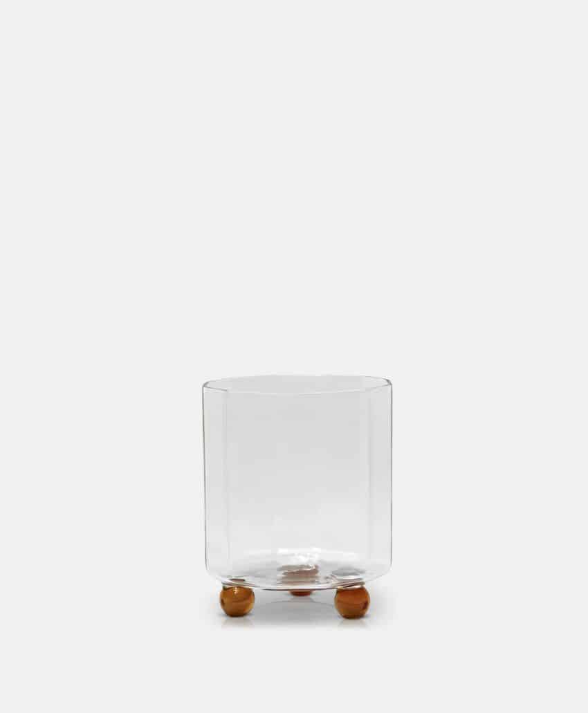 A clear glass container with a cylindrical shape, supported by three small round wooden feet, displayed against a plain white background.