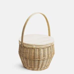 A round, woven wicker basket with a sturdy wooden handle and a flat wooden lid, set against a plain white background.