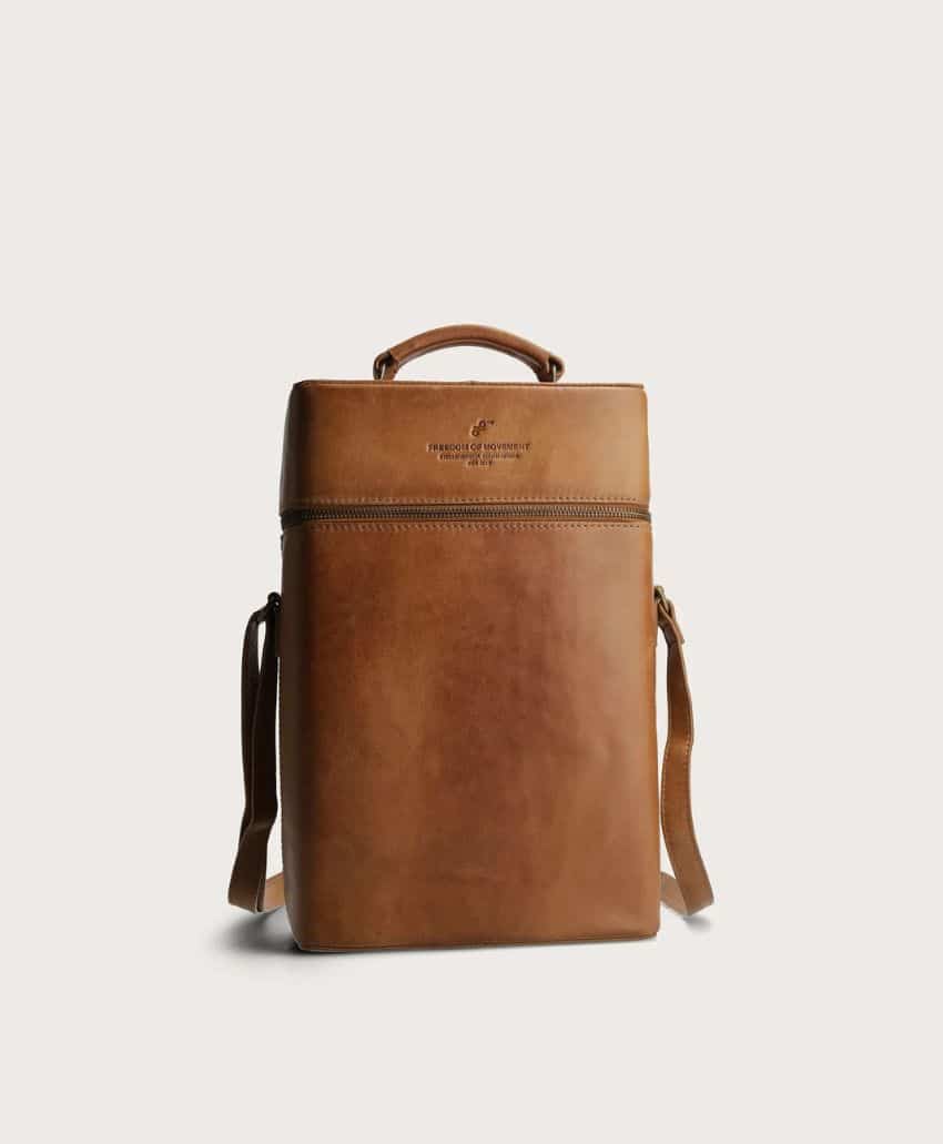 A brown leather backpack with a top handle and adjustable shoulder straps, featuring a zippered top section and embossed logo on the front, displayed against a plain off-white background.