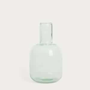 A clear, translucent glass vase with a short, wide body and a narrow, straight neck, set against a plain light background.