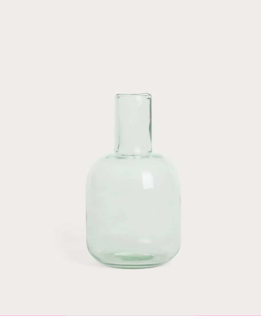 A clear, translucent glass vase with a short, wide body and a narrow, straight neck, set against a plain light background.