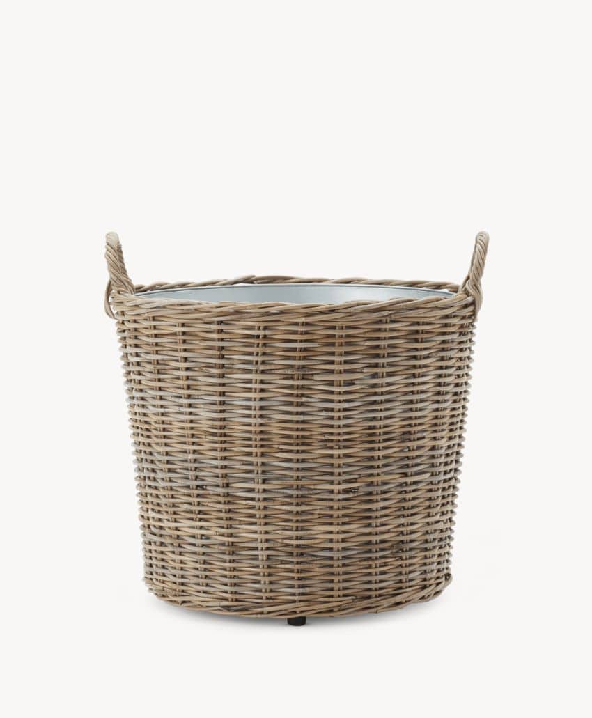 A round, woven wicker basket with two handles on either side, featuring a light brown color and a visible inner lining, placed against a plain white background.