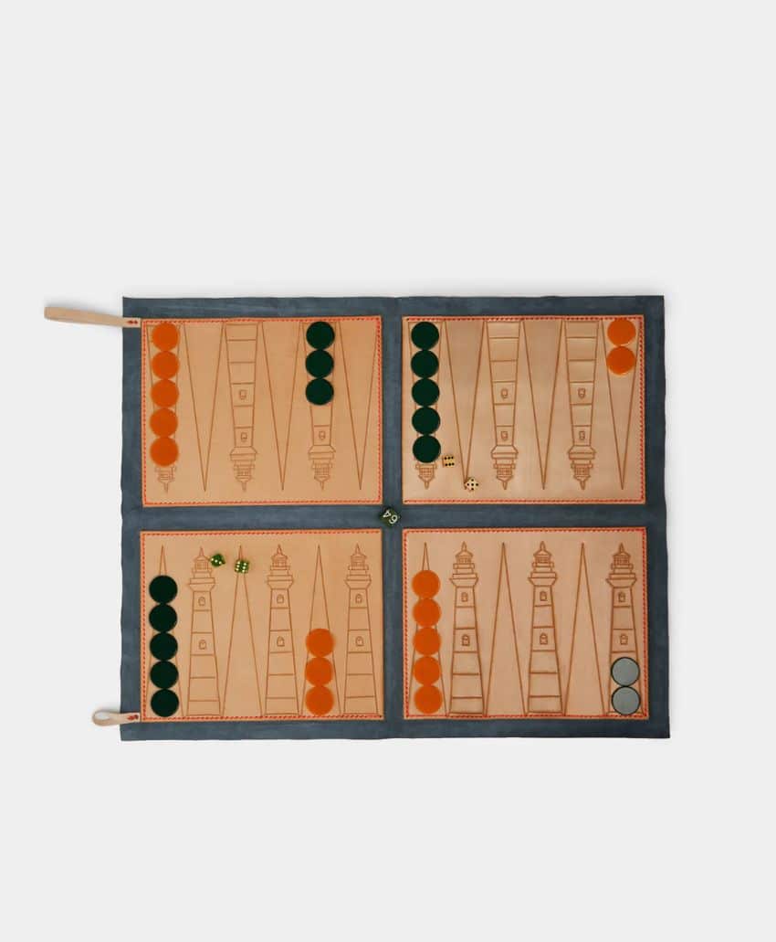 A flat, open backgammon board features tan and orange sections, with dark green and orange playing pieces arranged on the board, along with two dice and a doubling cube. The board rests on a white background.