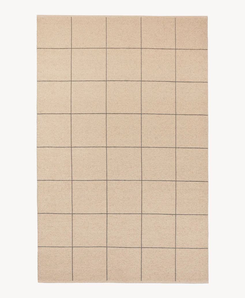 A rectangular beige rug with a simple grid pattern of evenly spaced thin dark lines forming squares across the surface.