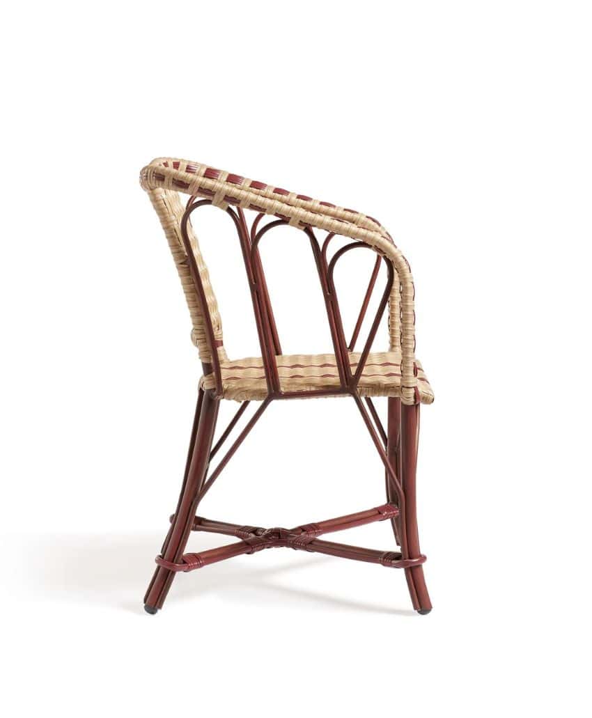 A side view of a rattan and wood chair with a curved backrest and woven seat, featuring natural and reddish-brown tones, set against a plain white background.