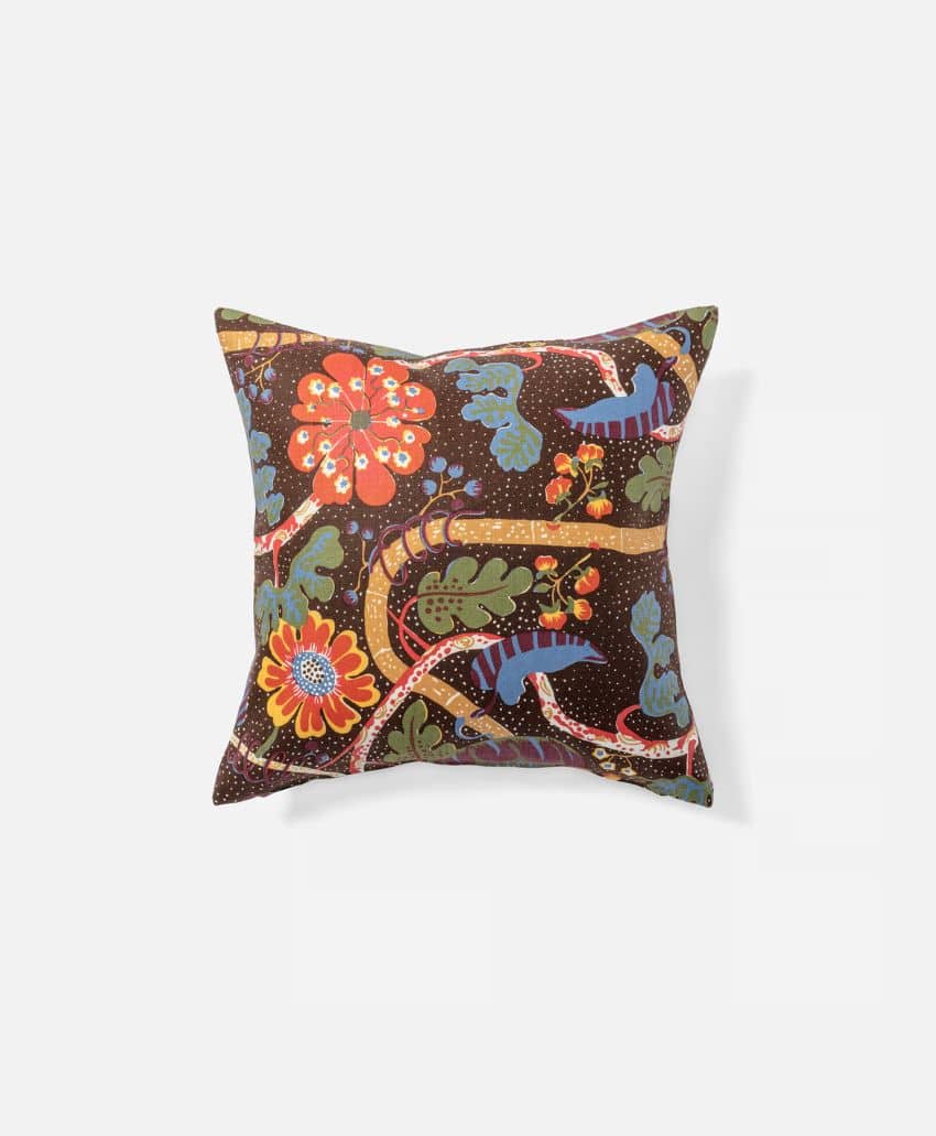 Square throw pillow with a dark brown background, decorated with colorful floral and leaf patterns in shades of red, orange, blue, green, and yellow.
