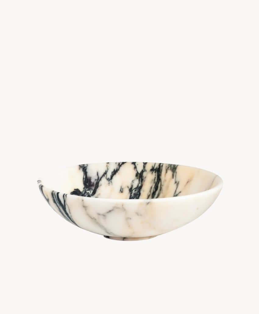 A shallow, round bowl made of white marble with dark grey and black veining, set against a plain white background.