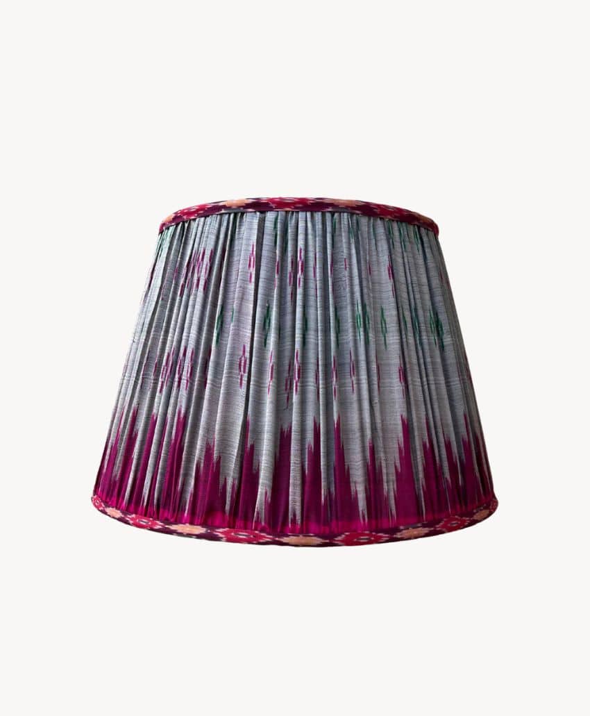 A pleated lampshade with a pattern of pink, green, and white vertical stripes, set against a plain white background.