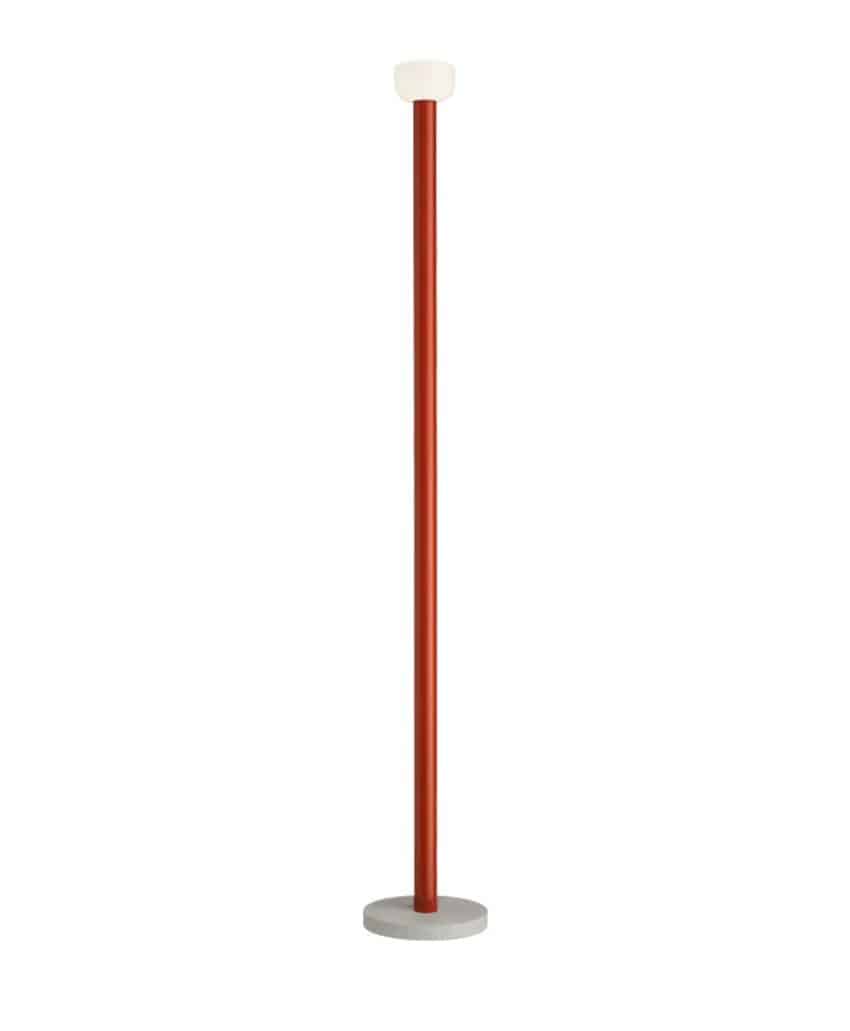 A modern floor lamp with a slim, red vertical pole, a round white lampshade on top, and a circular gray base. The design is minimalistic and contemporary.