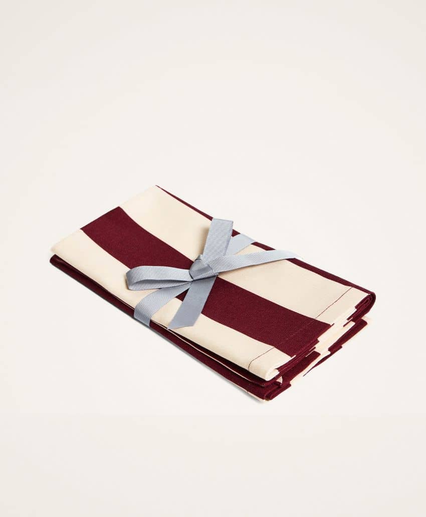 A folded cloth with maroon and cream stripes, tied neatly with a light blue ribbon, placed on a plain light background.