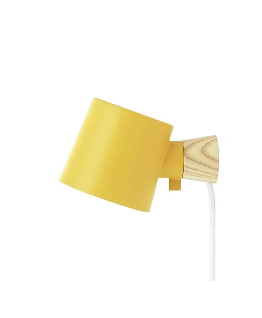 A modern wall-mounted lamp with a yellow metal shade, a light wood base, and a white cord, shown against a plain white background.