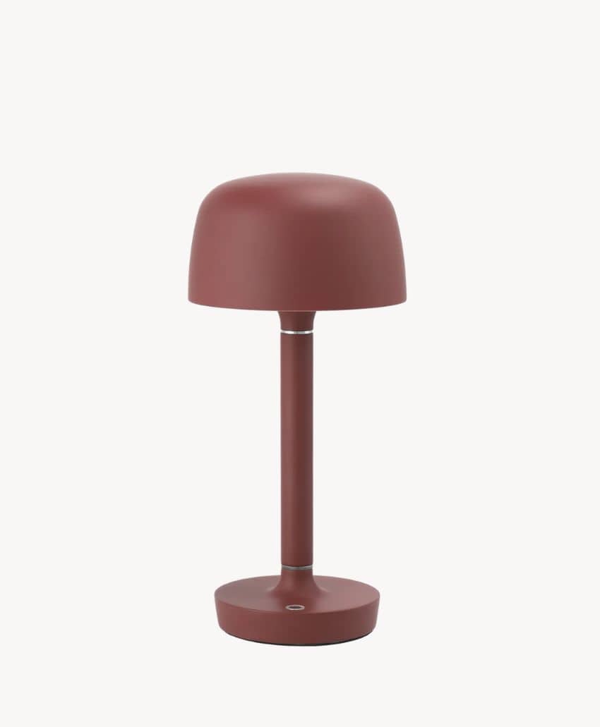 A modern, minimalist table lamp with a matte reddish-brown finish, featuring a dome-shaped shade, straight cylindrical stem, and round base, set against a plain white background.