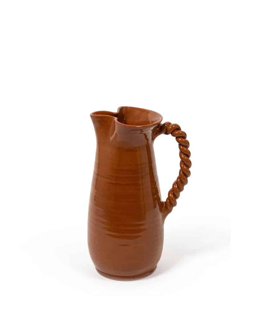 A tall, brown ceramic pitcher with a glossy finish and a twisted, ornate handle, set against a plain white background.