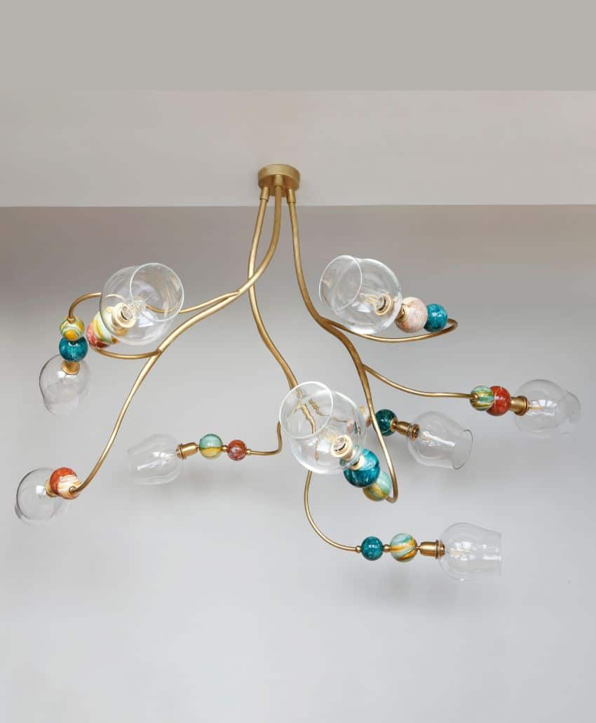 A modern ceiling light fixture with gold branches, colorful decorative beads, and clear glass bulb covers, resembling an abstract, organic design against a plain white ceiling.