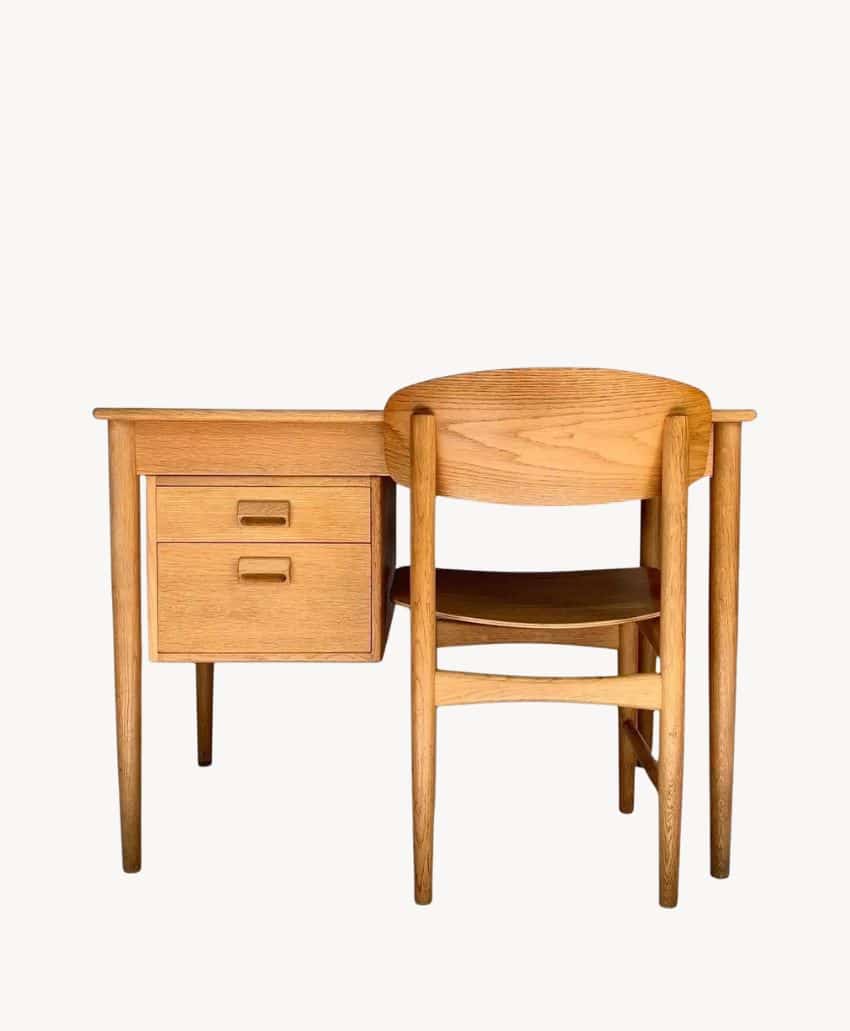A wooden desk with two drawers and a matching wooden chair are placed together against a plain white background.