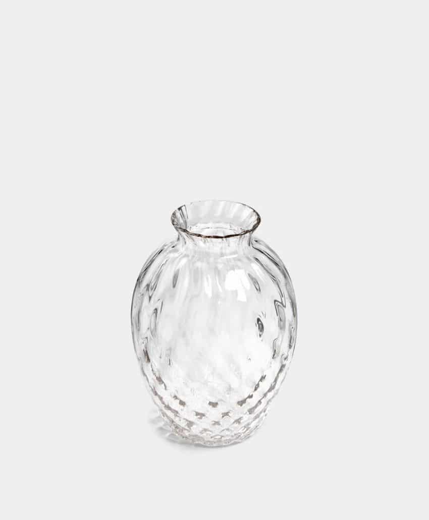 Round, clear glass vase with a textured, dimpled surface and a narrow, slightly flared opening, set against a plain light gray background.