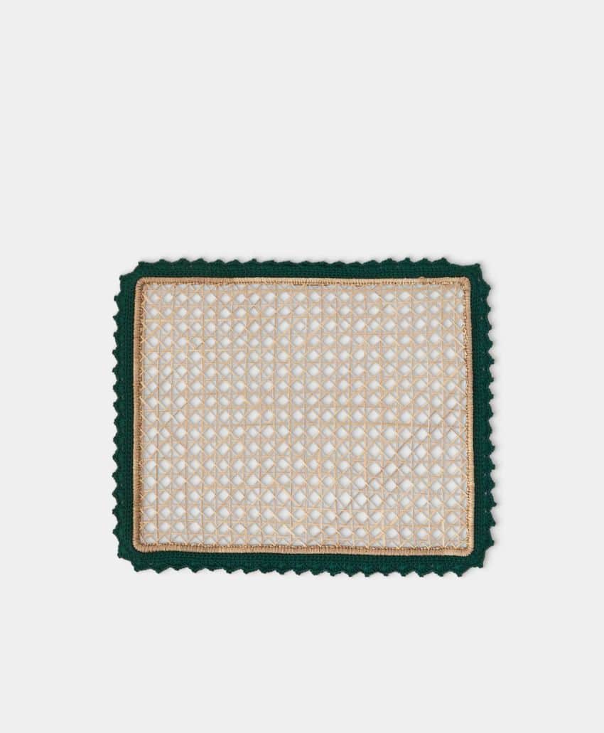 A rectangular placemat with a woven beige and white checkered pattern, bordered by a dark green scalloped edge and a thin gold trim, set against a plain light background.