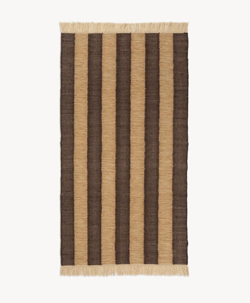 Rectangular woven rug with alternating wide vertical stripes in beige and dark brown, finished with short beige fringe on the shorter ends, displayed on a white background.