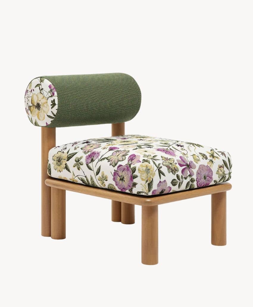A modern wooden chair with round legs, a green cylindrical backrest with a floral pattern on one end, and a seat cushion upholstered in white fabric with yellow, purple, and green floral designs.
