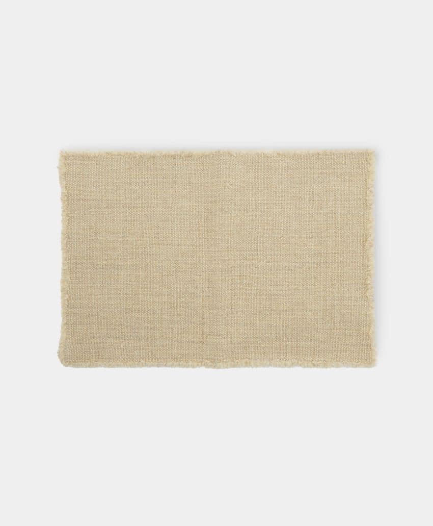 A rectangular beige woven placemat with slightly frayed edges, displayed on a plain white background.