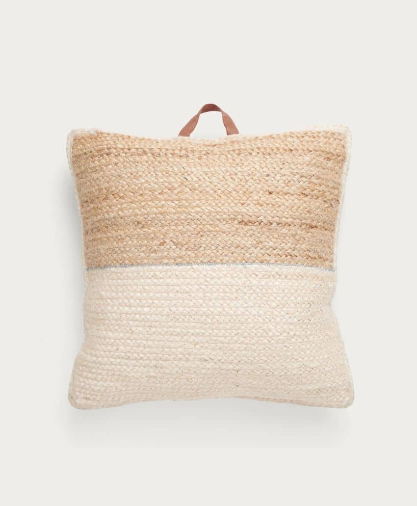 A square cushion with a textured, woven design in two sections: the top half is light brown and the bottom half is off-white. A small tan loop handle is attached at the top center.