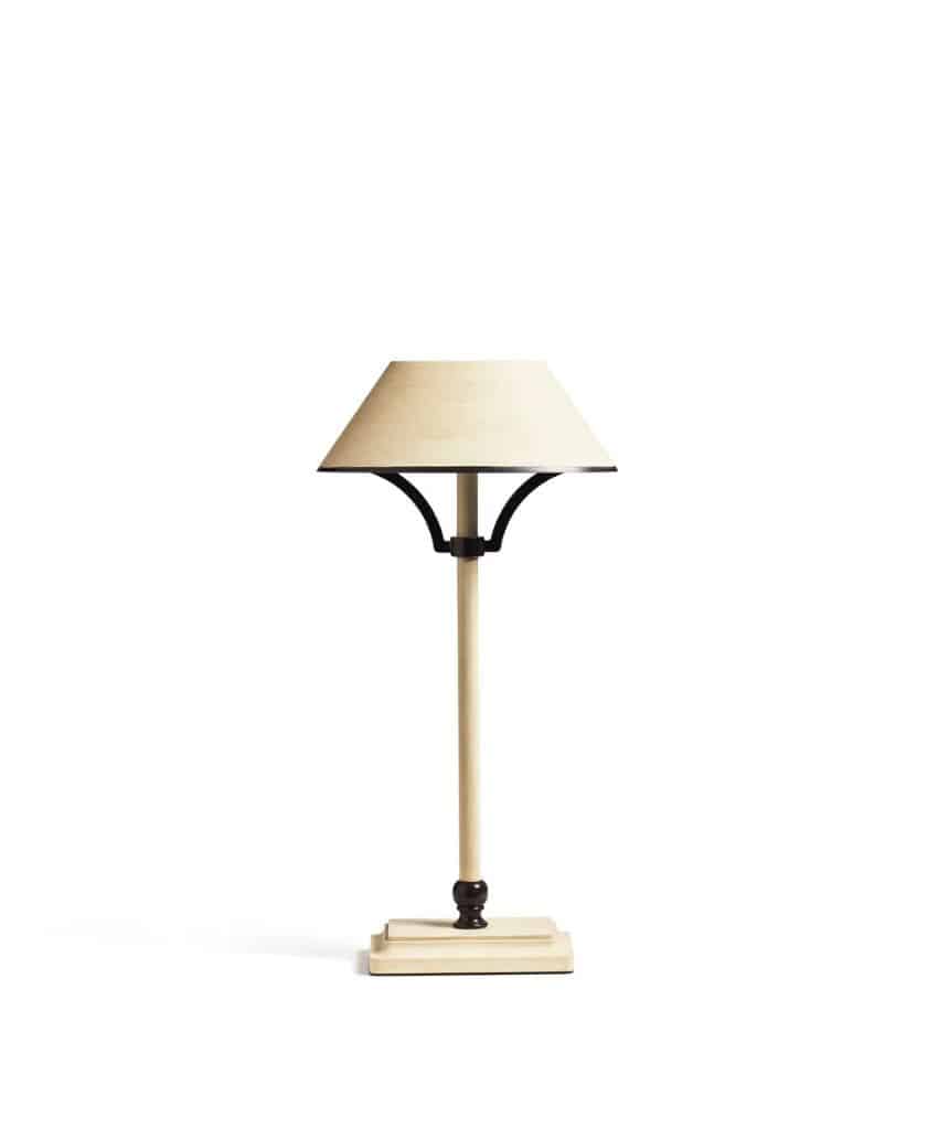 A beige table lamp with a tapered lampshade, straight stem, and dark accents on a square base, set against a plain white background.