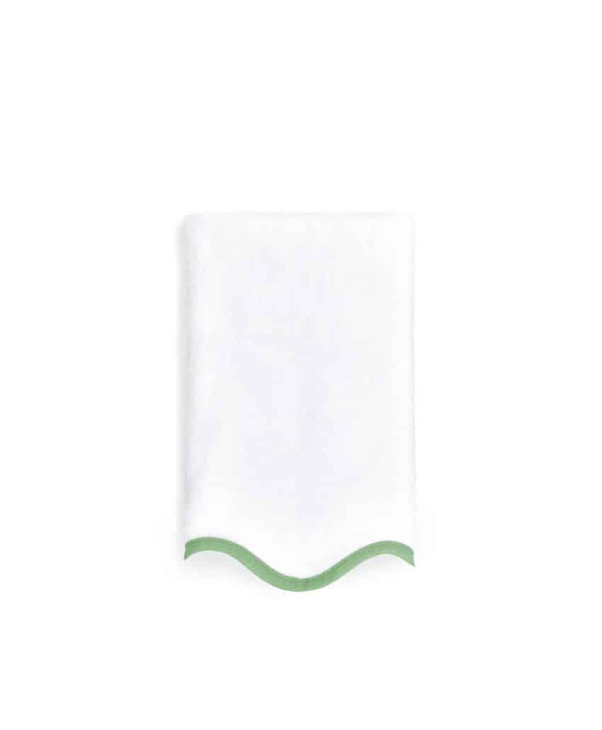 A neatly folded white towel with a green border along one edge, placed against a plain white background.
