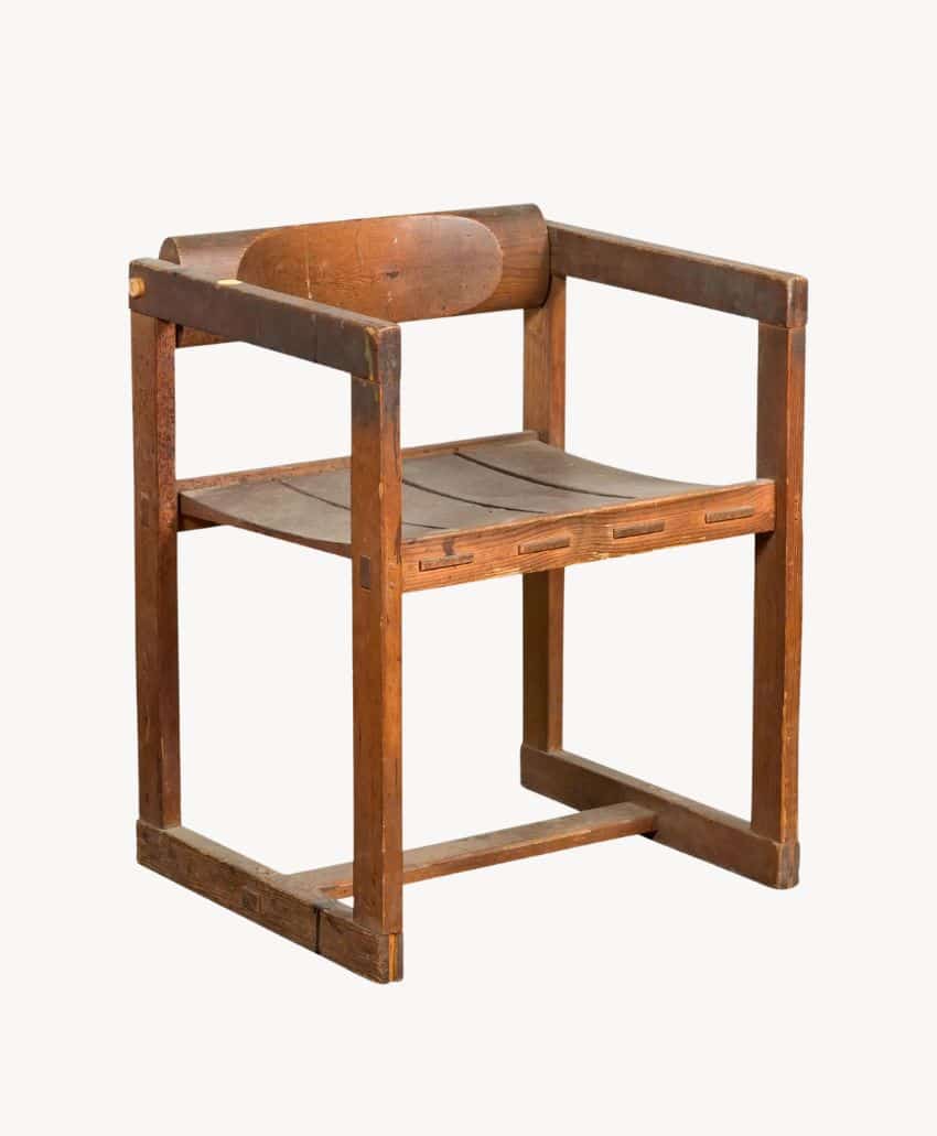 A wooden chair with a square, minimalist frame, flat seat, and straight backrest. The design is simple and rustic, showing visible wear and joints, with no cushions or armrest padding.