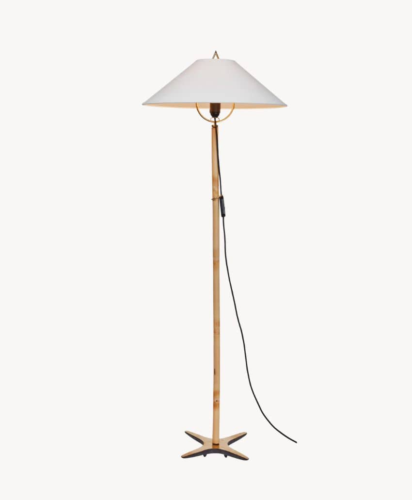 A tall floor lamp with a wooden stand, star-shaped base, white conical lampshade, and a black power cord hanging to the side.