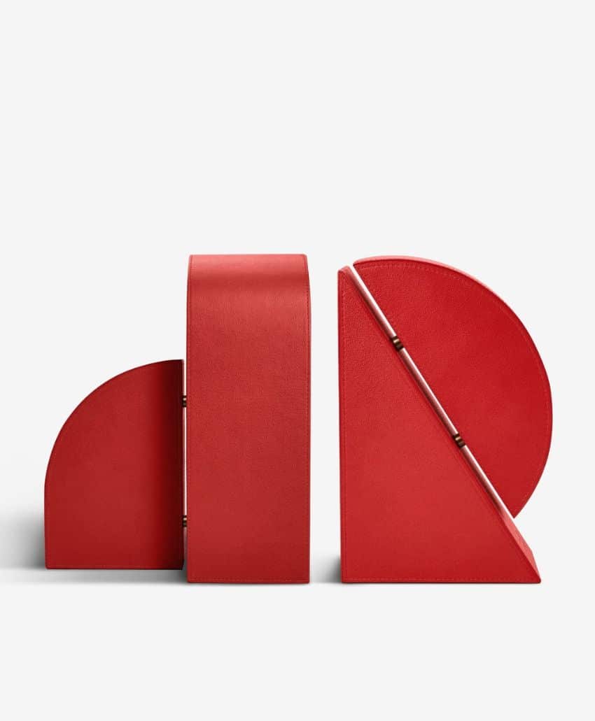 Three geometric red bookends of varying shapes—a semicircle, a rounded arch, and a triangle with a curved edge—are arranged side by side against a plain white background.