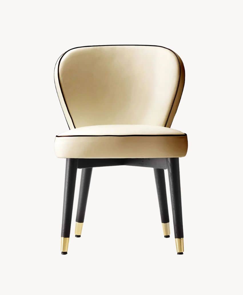 A modern chair with a curved, cream-colored upholstered backrest and seat, black legs, and gold-colored caps on the feet, shown against a plain white background.