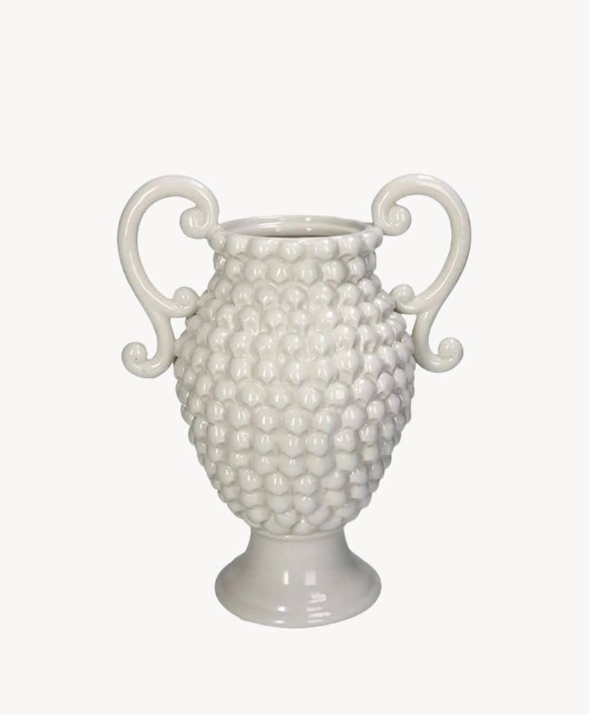 A white ceramic vase with a textured surface resembling clusters of grapes and two ornate, curled handles on either side, displayed against a plain white background.