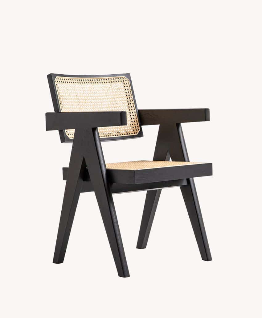 A modern armchair with black wooden frame, angled legs, and woven cane seat and backrest, photographed on a plain light background.