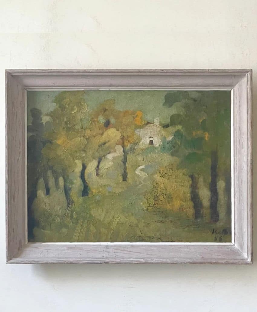 Framed painting of a soft, impressionistic landscape with green and yellow tones, depicting trees, a winding path, and a small white building in the background.