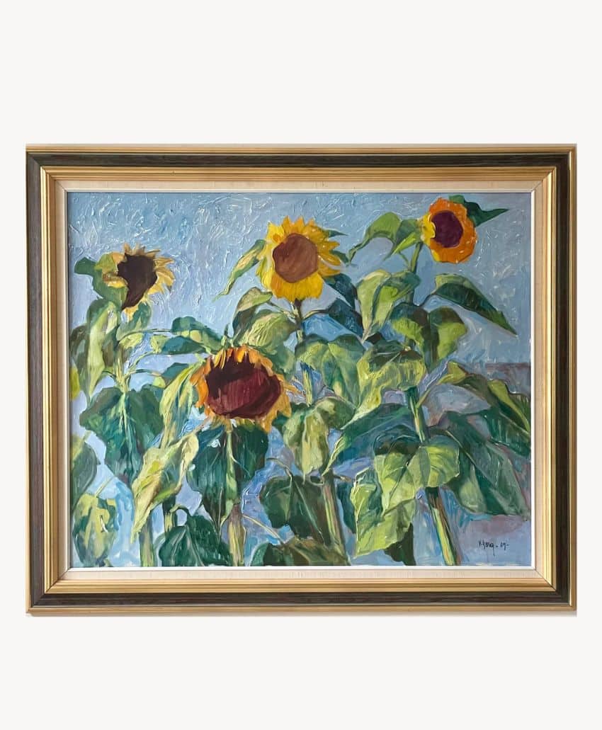 Framed painting of four sunflowers with large green leaves against a blue sky background; two sunflowers face forward, and two are turned to the side.