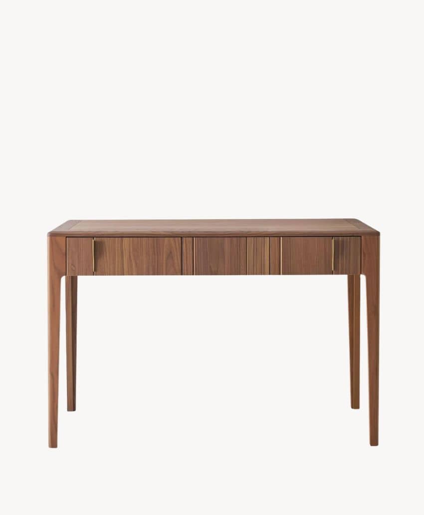 A minimalist wooden desk with four slender legs and a smooth surface, featuring three subtle front drawers with vertical grooves for handles, set against a plain white background.