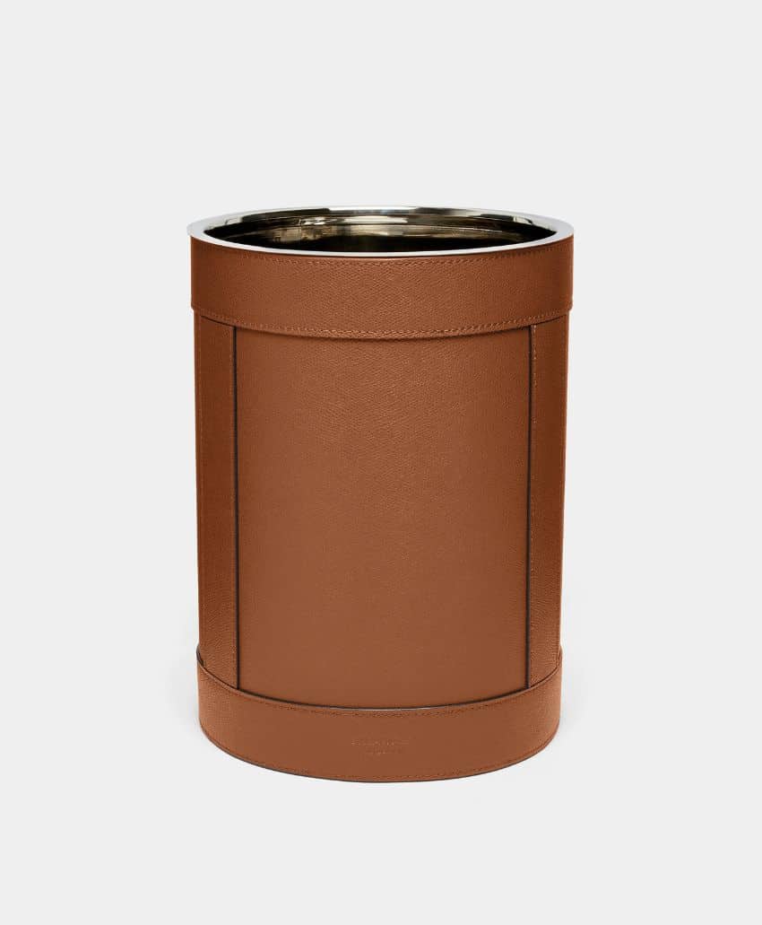 A cylindrical, brown leather waste bin with a metallic rim and interior, set against a plain white background.