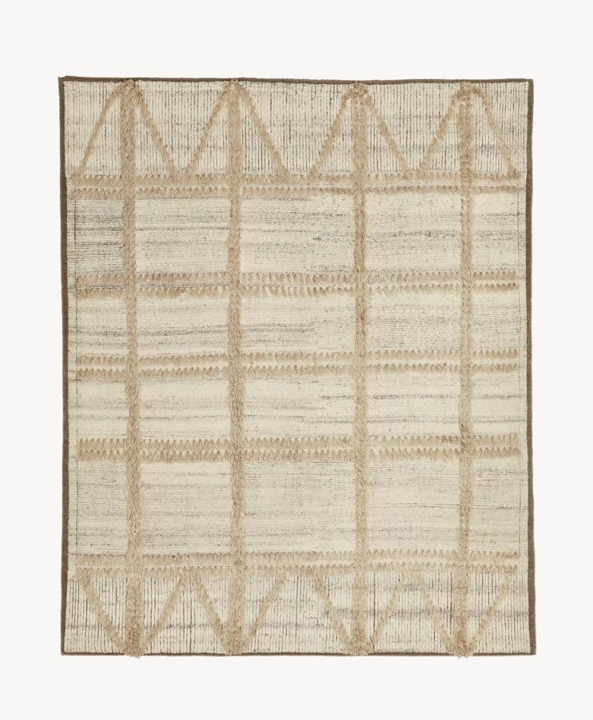 A rectangular area rug with a beige and light brown color scheme, featuring a grid pattern and triangular designs along the top and bottom edges. The rug has a subtle textured appearance.