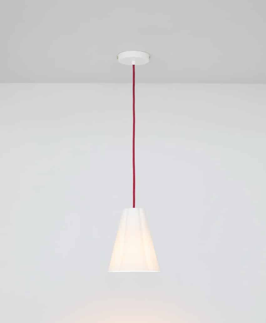 A white pendant light with a conical shade hangs from the ceiling by a red cord against a plain white wall and ceiling background.