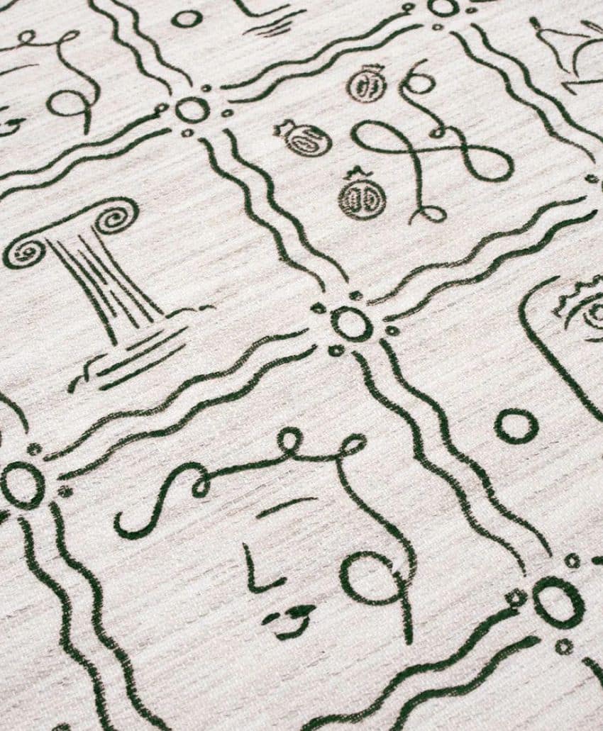 A beige rug with a pattern of dark green, abstract line drawings, including faces, swirls, ancient columns, and fruit, arranged within a grid of wavy squares.