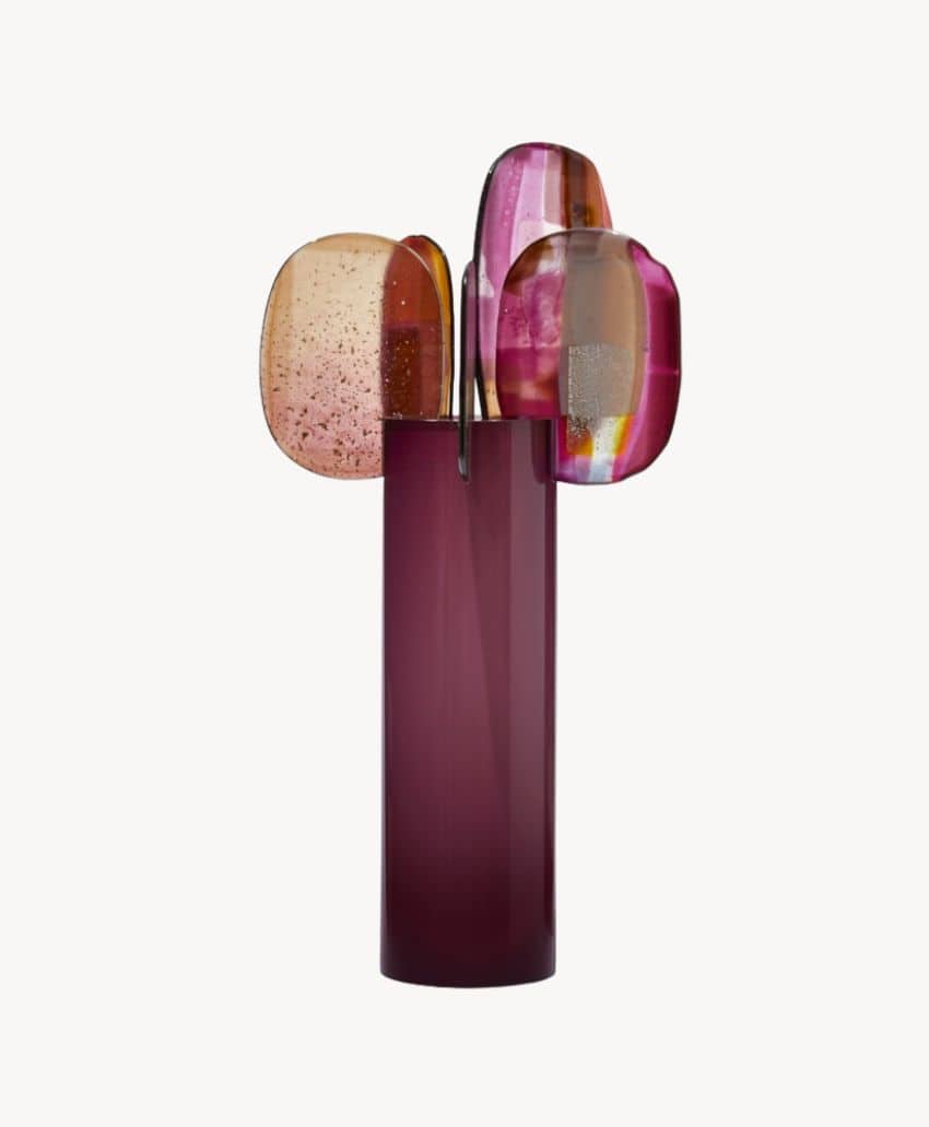 A modern sculptural vase with a tall, cylindrical purple base and three abstract, rounded glass shapes in pink, amber, and light orange hues emerging from the top.