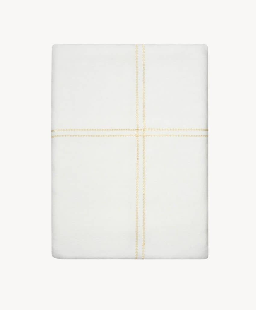 A folded white bedsheet featuring a simple yellow double-stitched cross pattern in the center, displayed against a plain white background.