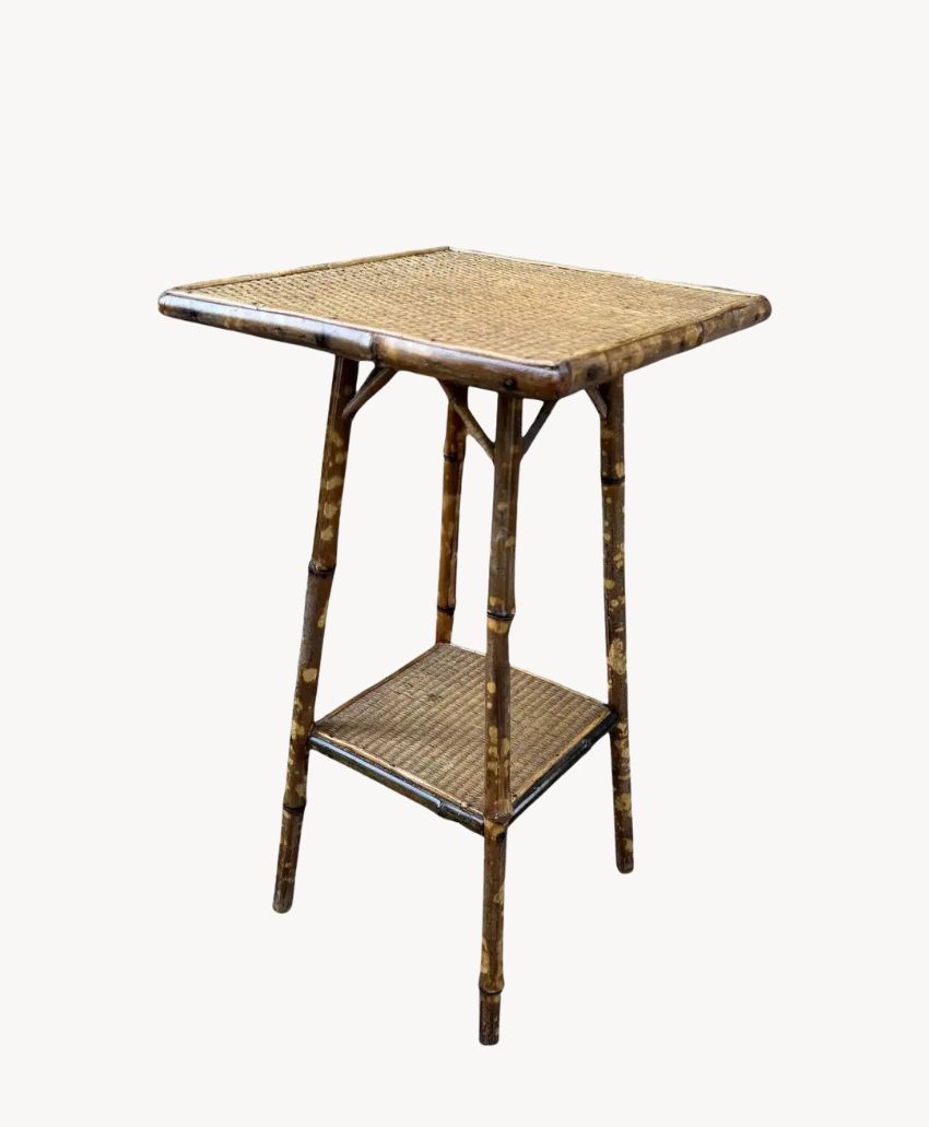 Square bamboo side table with a woven rattan top and lower shelf, featuring four slender legs and a natural brown finish.