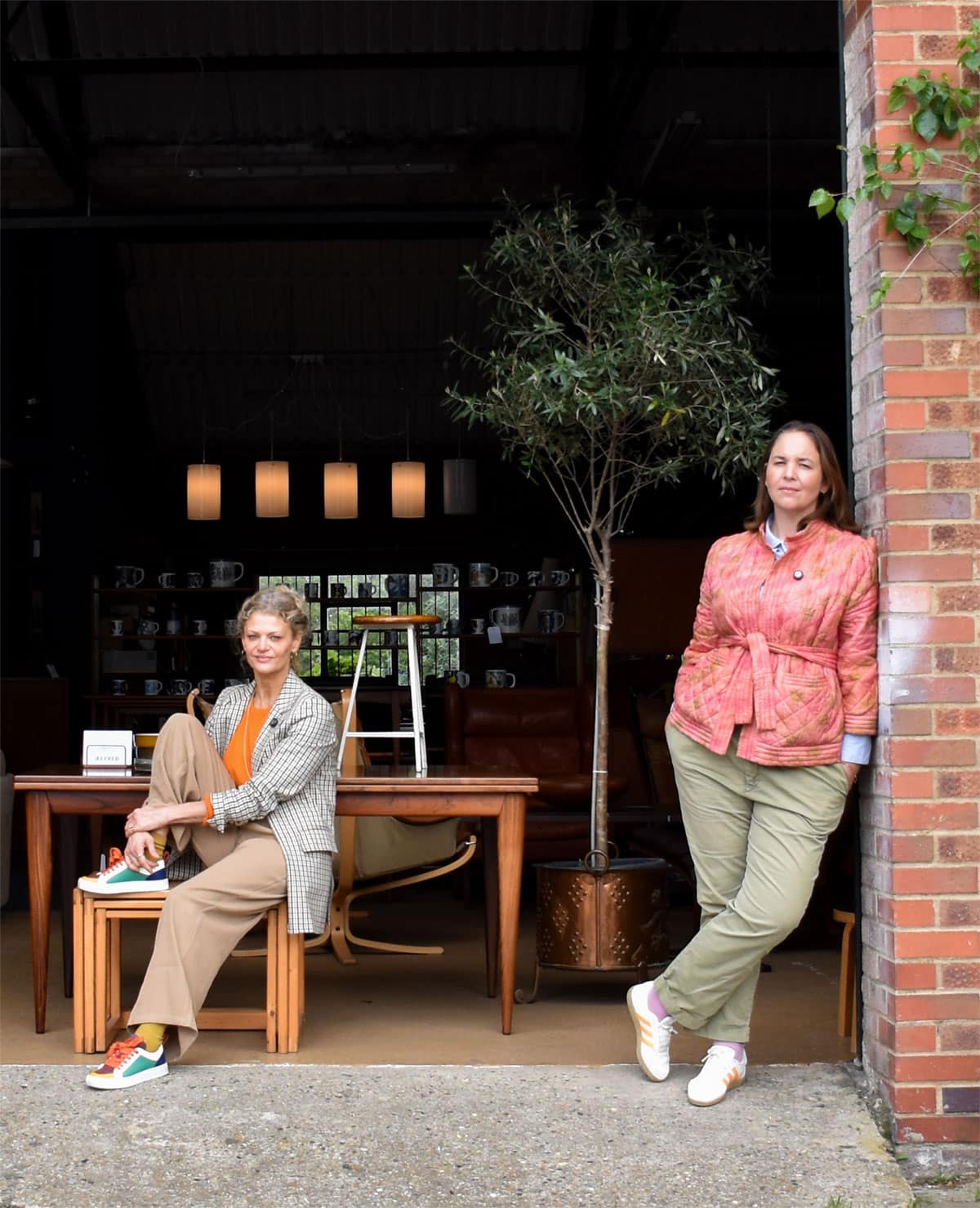 A couple of women leaning against a wall.