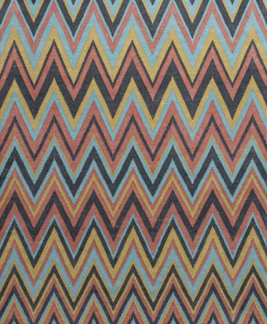 A geometric pattern of repeating zigzag chevrons in red, blue, yellow, black, and orange, creating a vibrant and symmetrical design across the entire image.