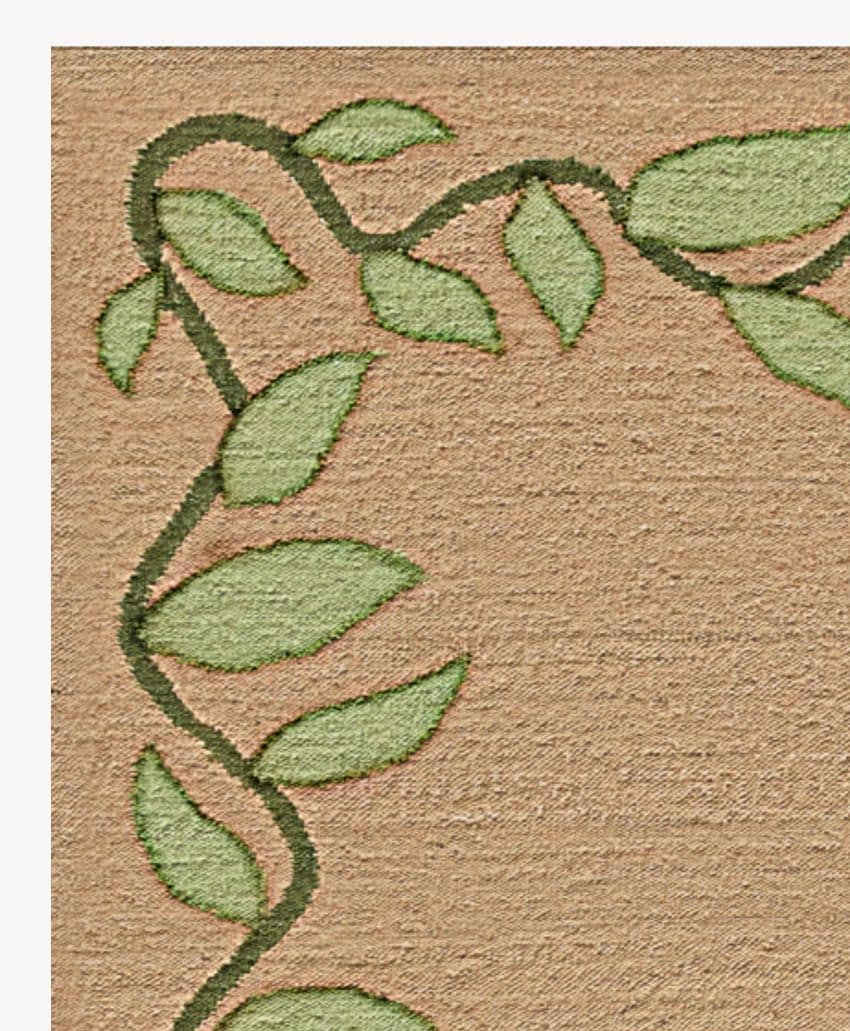 Embroidered green vine with leaves curves along the top and left edges of a tan textured fabric background. The design appears decorative and natural.