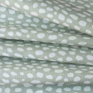 Stacked layers of pale green fabric with an irregular white dot pattern, creating a soft, textured appearance.