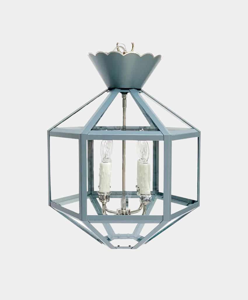 A geometric, cage-style hanging pendant light fixture with a blue-gray metal frame and two candle-shaped bulbs inside, suspended from a matching scalloped ceiling mount against a plain white background.