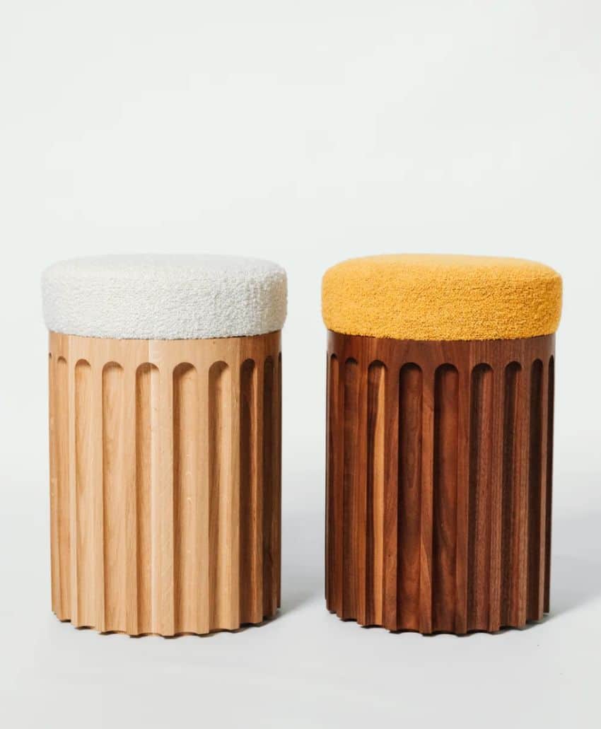 Two cylindrical stools with ribbed wooden bases; the left stool is light wood with a white textured cushion, and the right stool is dark wood with a mustard yellow textured cushion, both against a plain background.